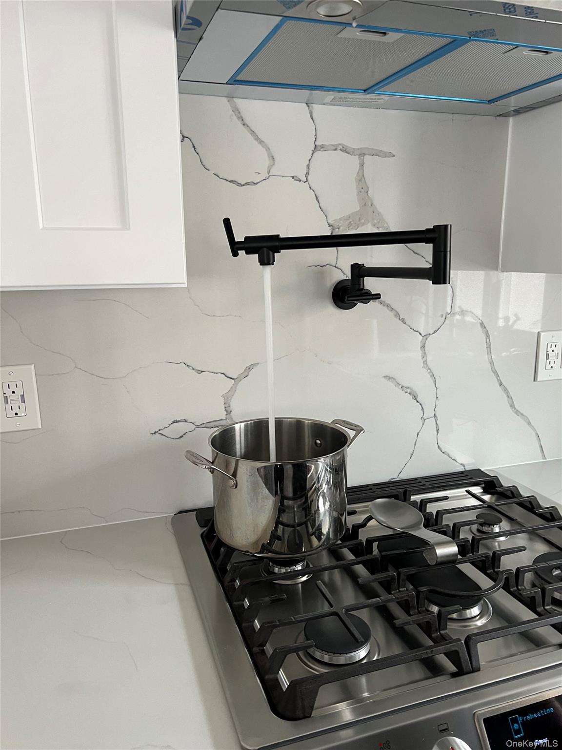 1580 North Jerusalem Road Merrick, NY 11566 - Photo 14 of 36 Kitchen featuring a pot filler faucet, a stainless steel gas range, and white countertops with a patterned backsplash