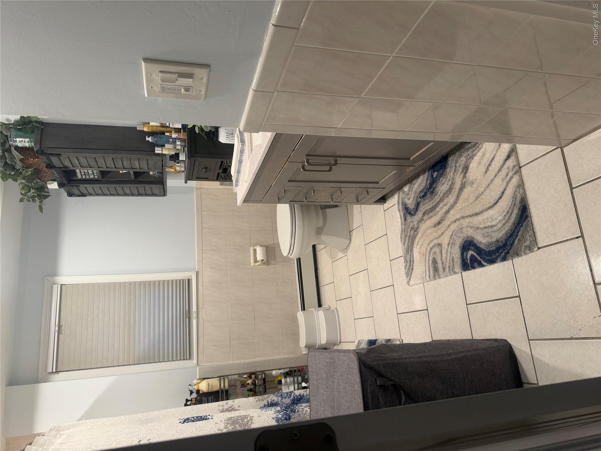 1580 North Jerusalem Road Merrick, NY 11566 - Photo 23 of 36 Bathroom featuring light-colored tiled floors, a window with blinds, and a vanity with a light-colored countertop