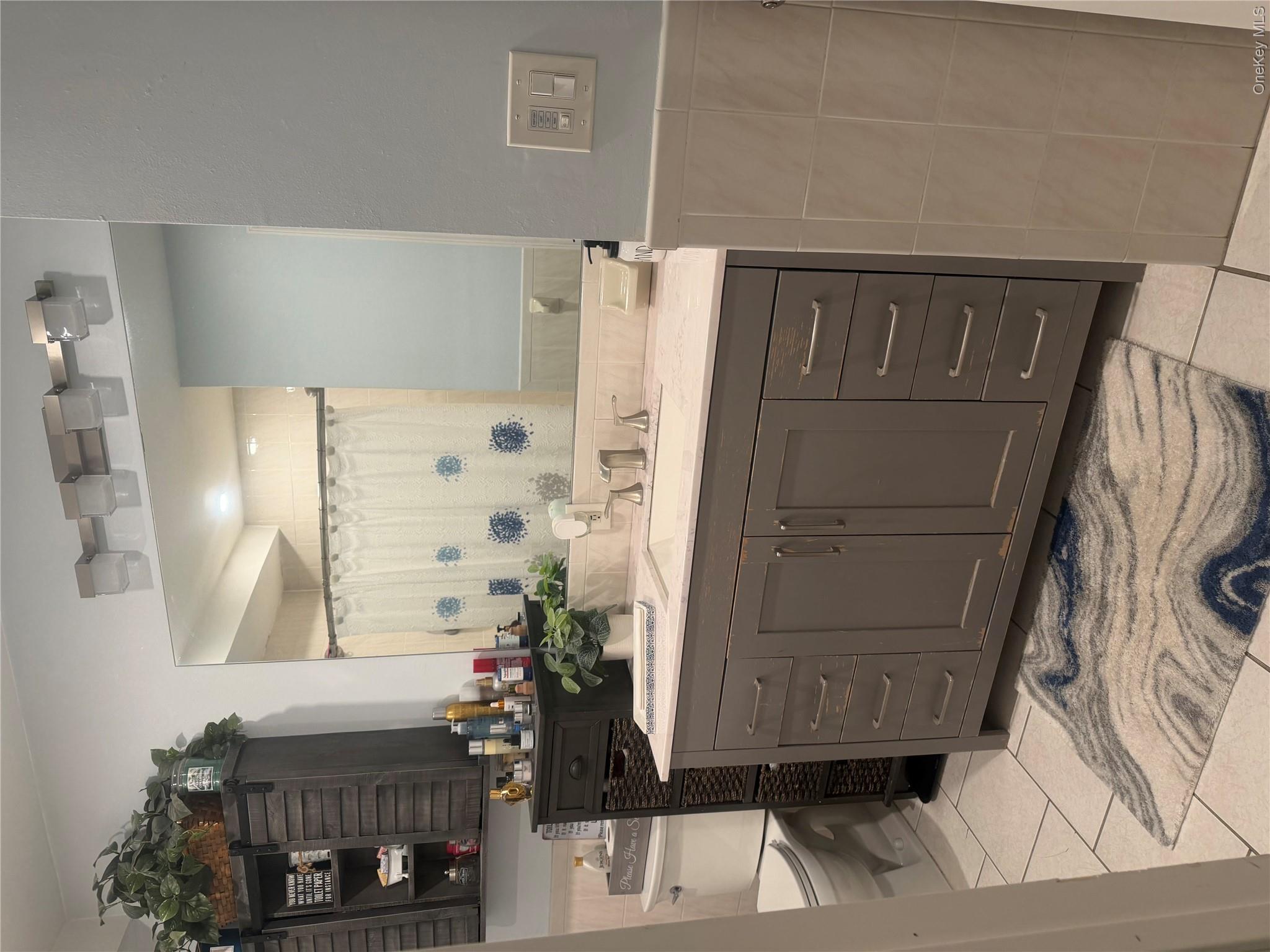 1580 North Jerusalem Road Merrick, NY 11566 - Photo 24 of 36 Bathroom featuring a vanity with a light-colored countertop, an integrated sink, and a large mirror