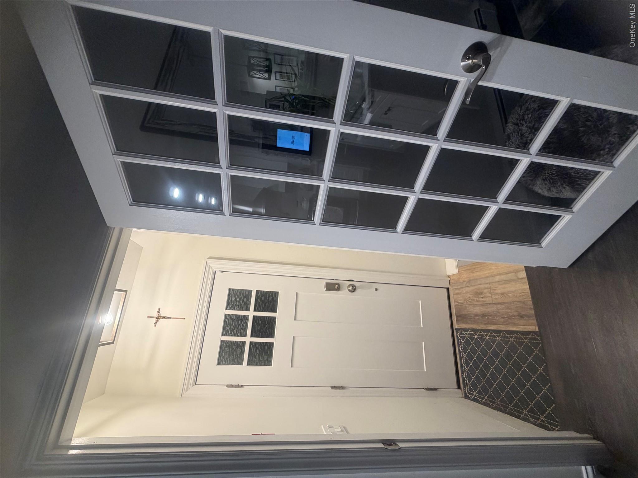 1580 North Jerusalem Road Merrick, NY 11566 - Photo 25 of 36 The property features a white paneled entry door with glass inserts, complemented by a glass-paned interior door, and dark flooring throughout