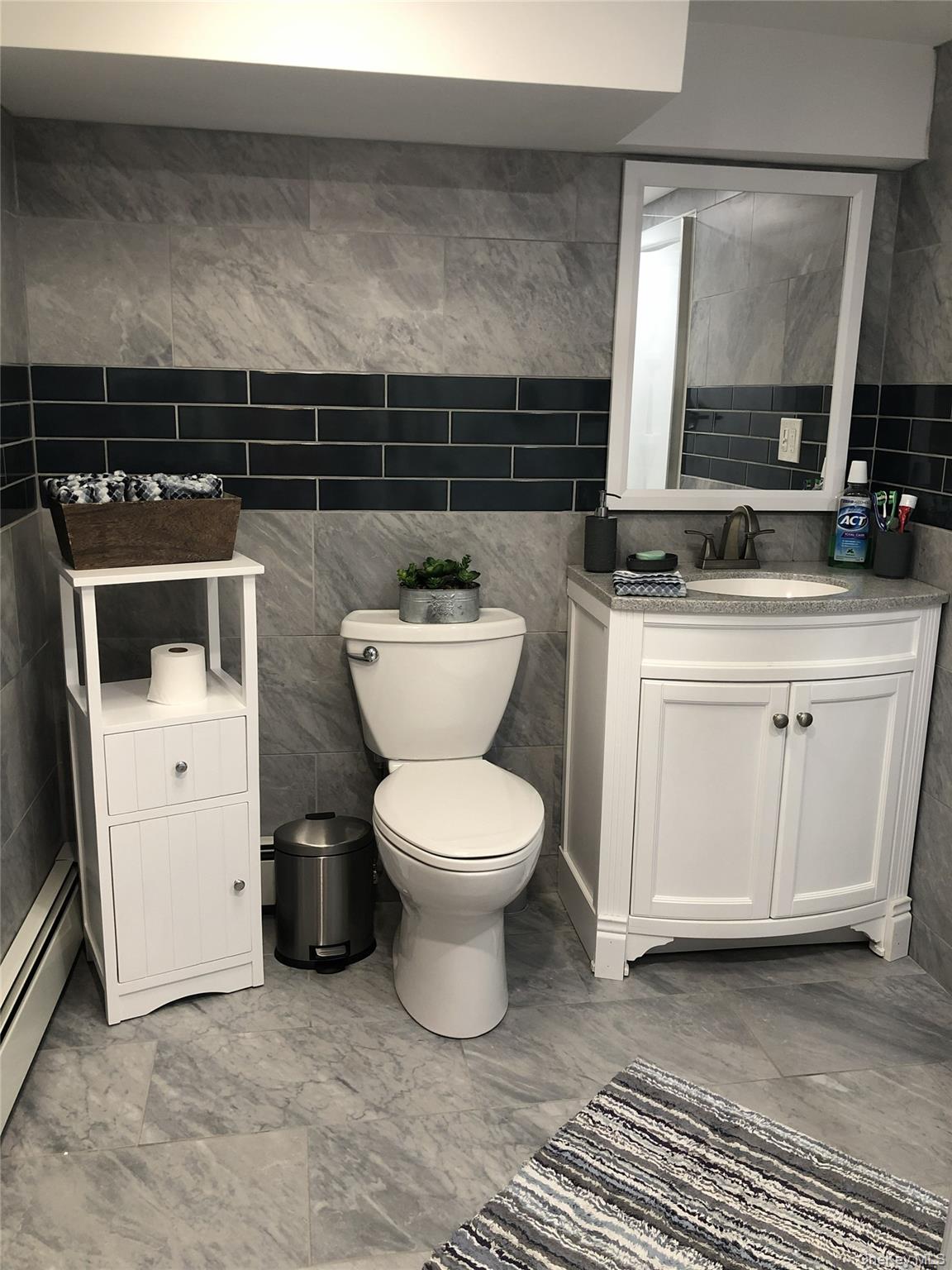 1580 North Jerusalem Road Merrick, NY 11566 - Photo 30 of 36 Bathroom featuring grey marble-style tiled walls and flooring, accented with a dark tiled stripe