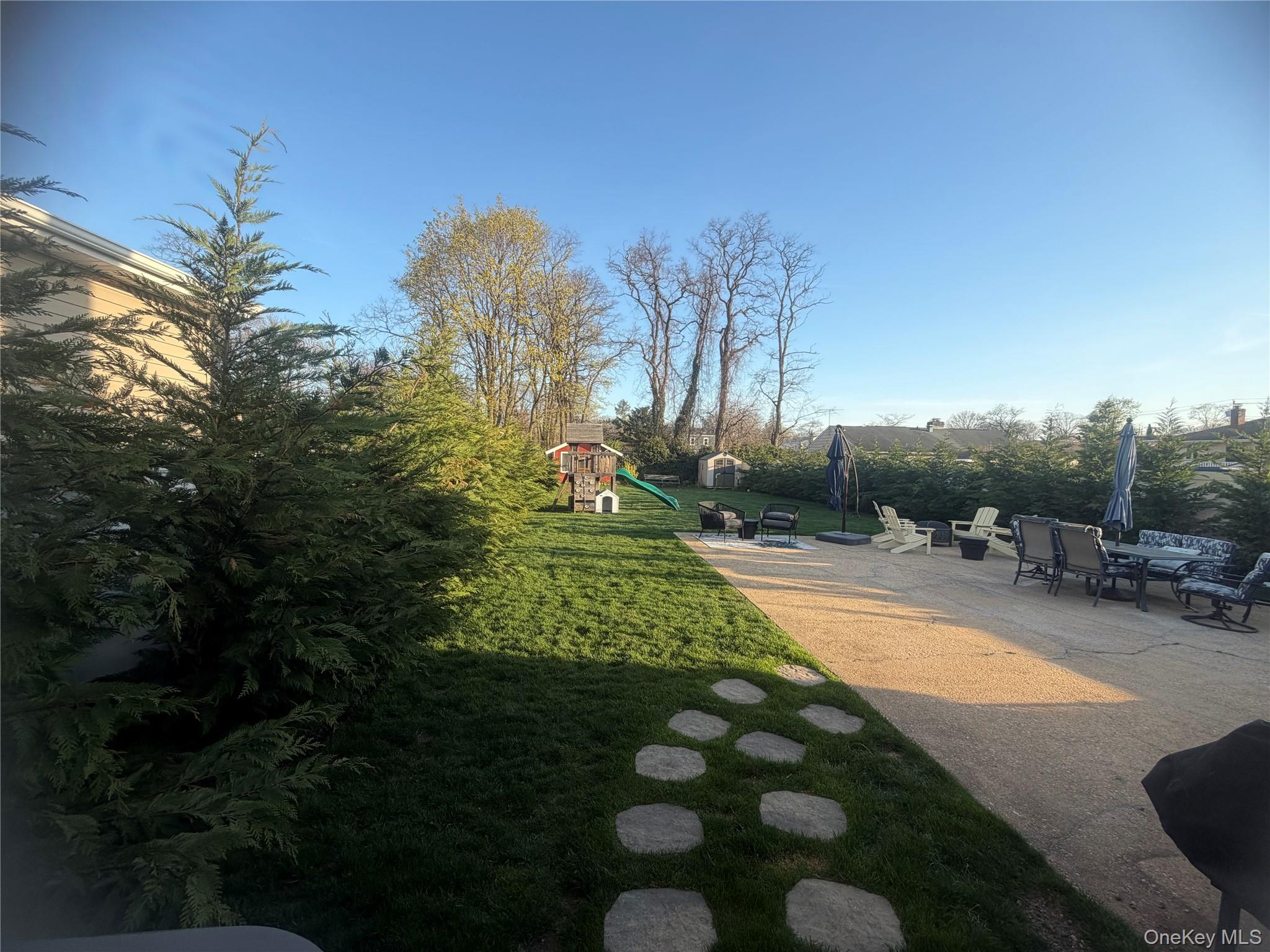 1580 North Jerusalem Road Merrick, NY 11566 - Photo 34 of 36 Expansive yard featuring a well-maintained lawn, mature trees, and a spacious paved patio area