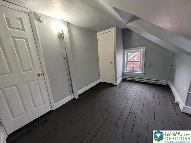 a view of an empty room with wooden floor and closet