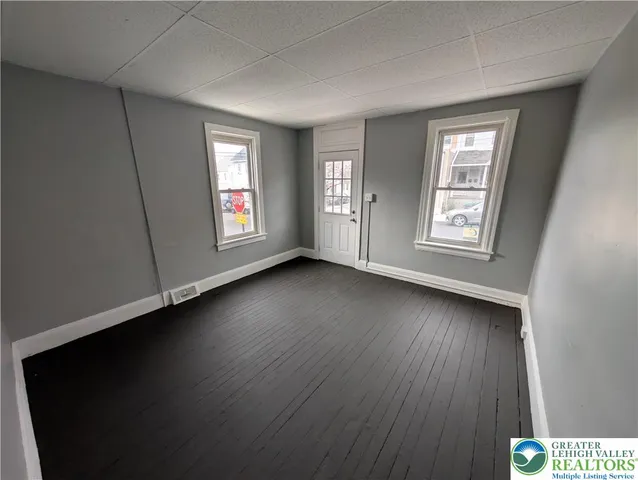 a view of an empty room with wooden floor and window