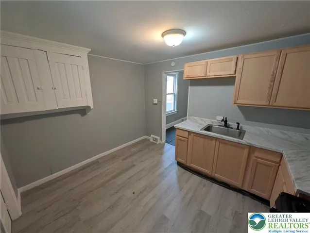 a room with granite countertop white cabinets and wooden floor