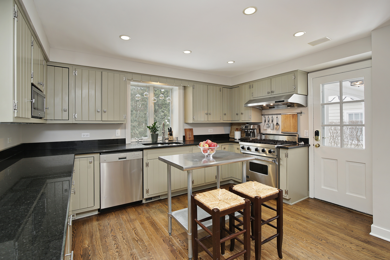 1309 Ridgewood Drive Northbrook, IL 60062 - Photo 5 of 18 a kitchen with kitchen island granite countertop wooden floors and white cabinets