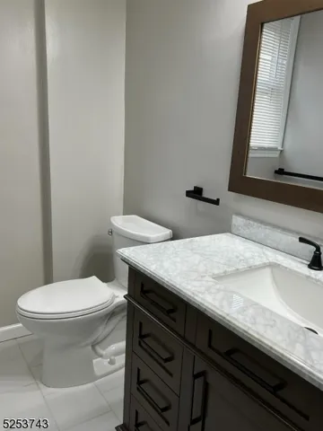 a bathroom with a granite countertop toilet sink and mirror