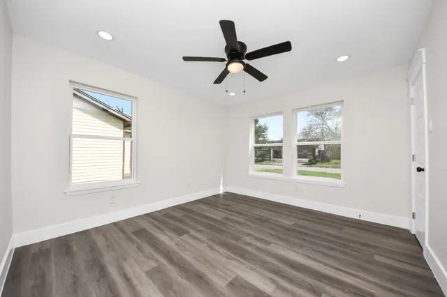 an empty room with wooden floor and ceiling fan