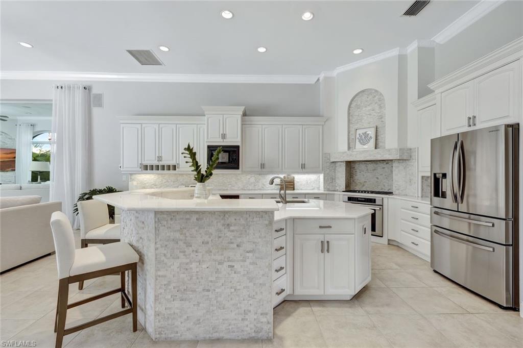 10072 Orchid Ridge Lane Estero, FL 34135 - Photo 16 of 48 a kitchen with kitchen island a sink stove and refrigerator
