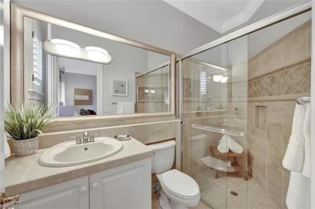 a bathroom with a sink a toilet a mirror and shower