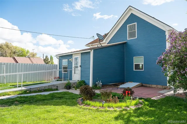 a backyard of a house with plants and large tree