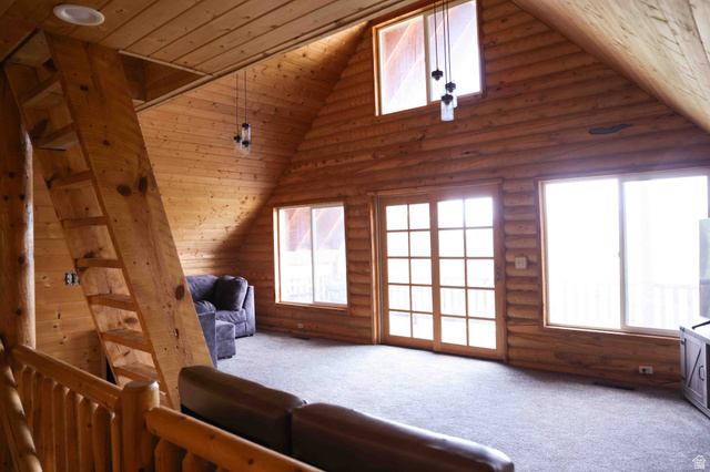 15253 Mill Road, Unit 62 Huntsville, UT 84317 - Photo 27 of 48 Vaulted ceiling great room featuring log wall construction, a wooden ladder-style staircase, two large windows, a glass-paneled double door, and a built-in recessed ceiling light