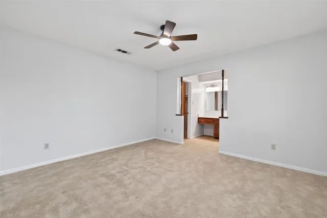 an empty room with chandelier fan and windows