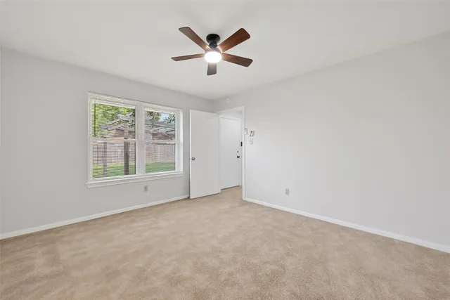 an empty room with ceiling fan and windows