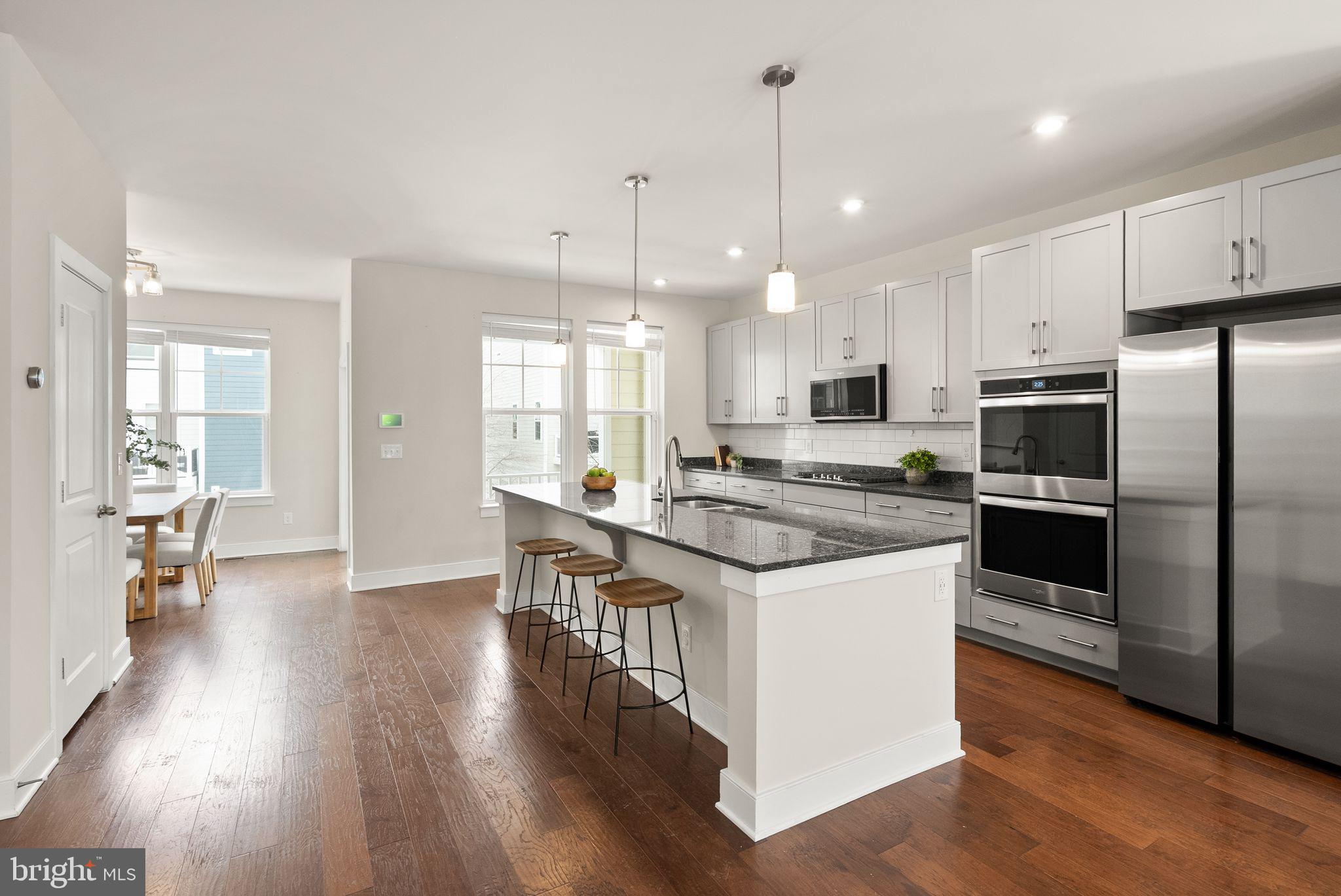 17762 Kingfisher Isle Road Dumfries, VA 22026 - Photo 11 of 62 a kitchen with stainless steel appliances granite countertop a refrigerator a stove a sink and white cabinets with wooden floor