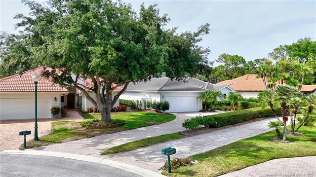 a front view of a house with a yard and a large tree