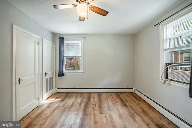 a view of empty room with wooden floor and fan