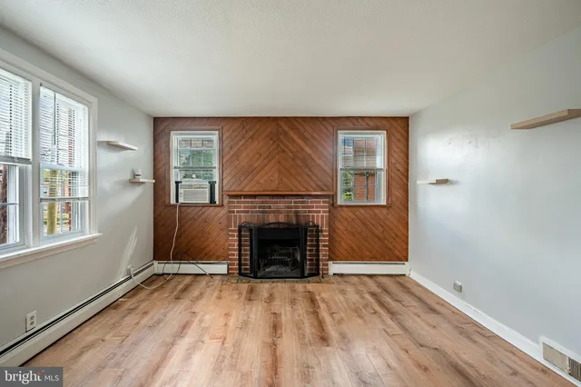 an empty room with windows fireplace and wooden floor