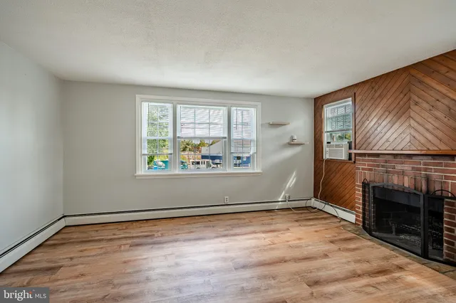 an empty room with windows and fireplace