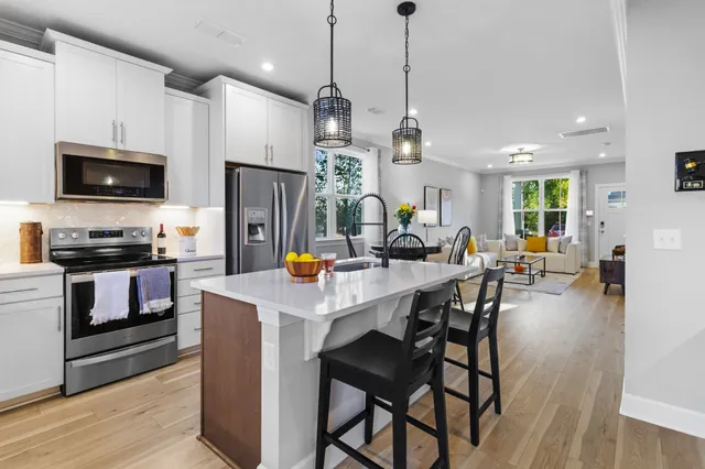 a view of kitchen center island dining table wooden floor and stainless steel appliances