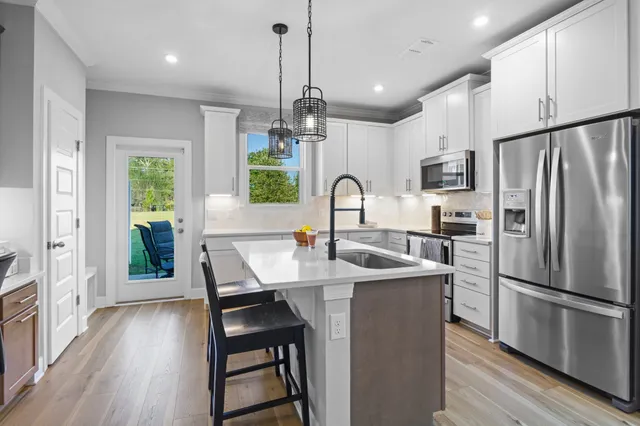 a kitchen with stainless steel appliances a sink a stove a refrigerator a center island and a window