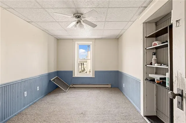 an empty room with chandelier fan and windows