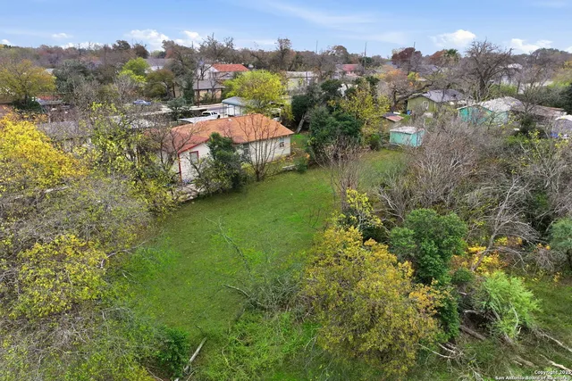 an aerial view of residential houses with outdoor space and trees