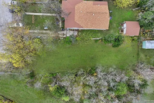 an aerial view of residential house with outdoor space and trees all around