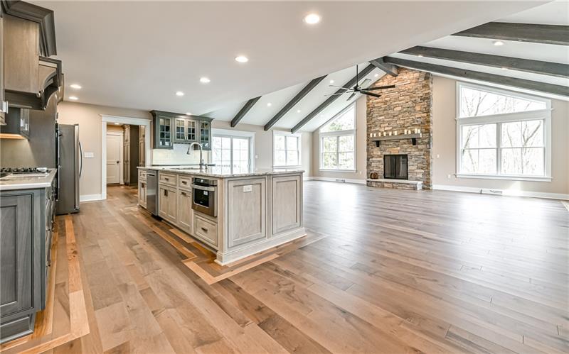 309 Parkhill Road Baden, PA 15005 - Photo 3 of 25 Enormous sun drenched great room with gleaming engineered wood flooring and inset border around room and cabinetry. Soaring floor to ceiling stacked stone wood burning fireplace accompany this stylish room.