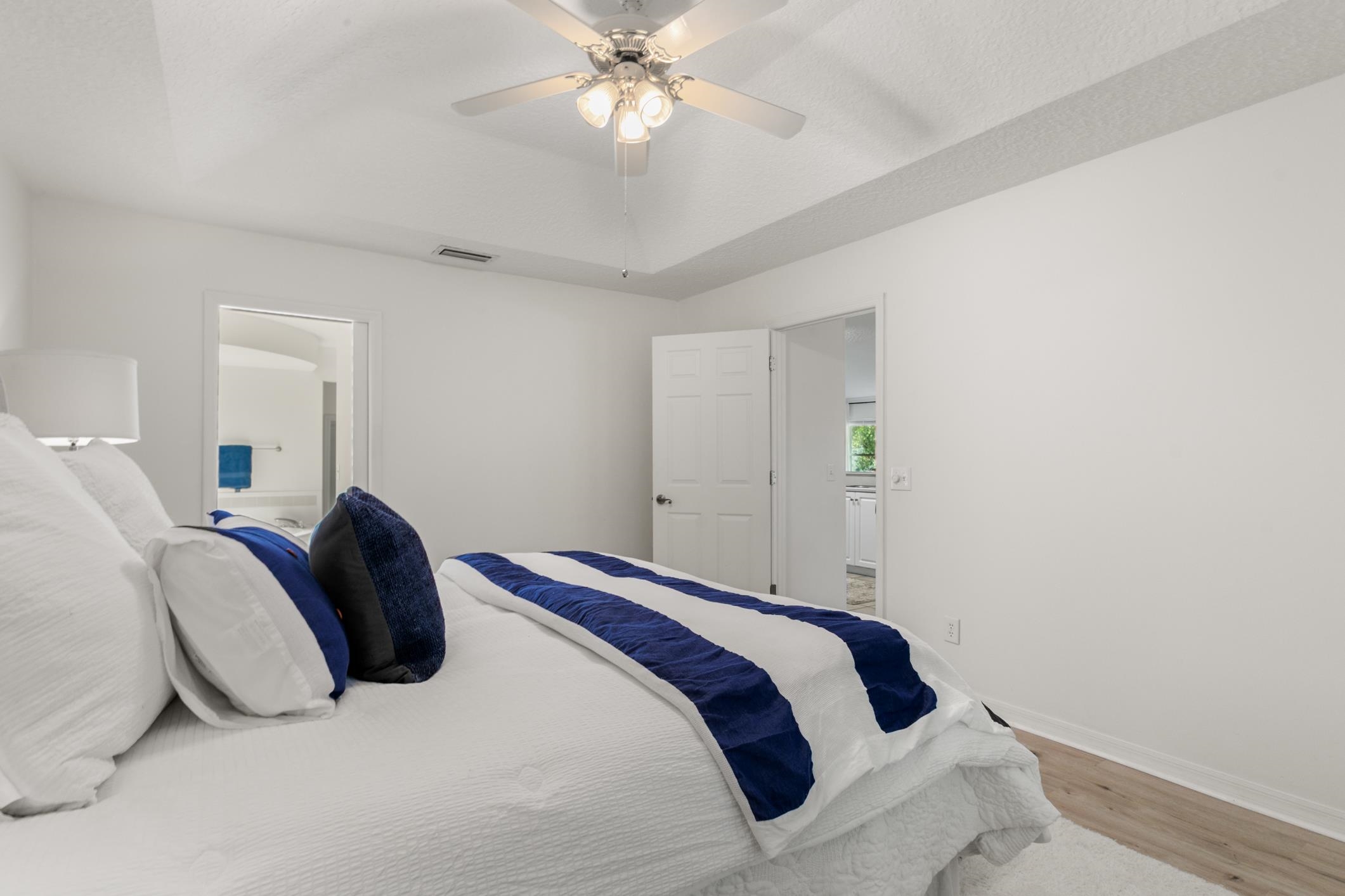 541 Peninsula Court St. Augustine, FL 32080 - Photo 37 of 63 Bedroom featuring a tray ceiling, ensuite bathroom, wood finished floors, and a ceiling fan