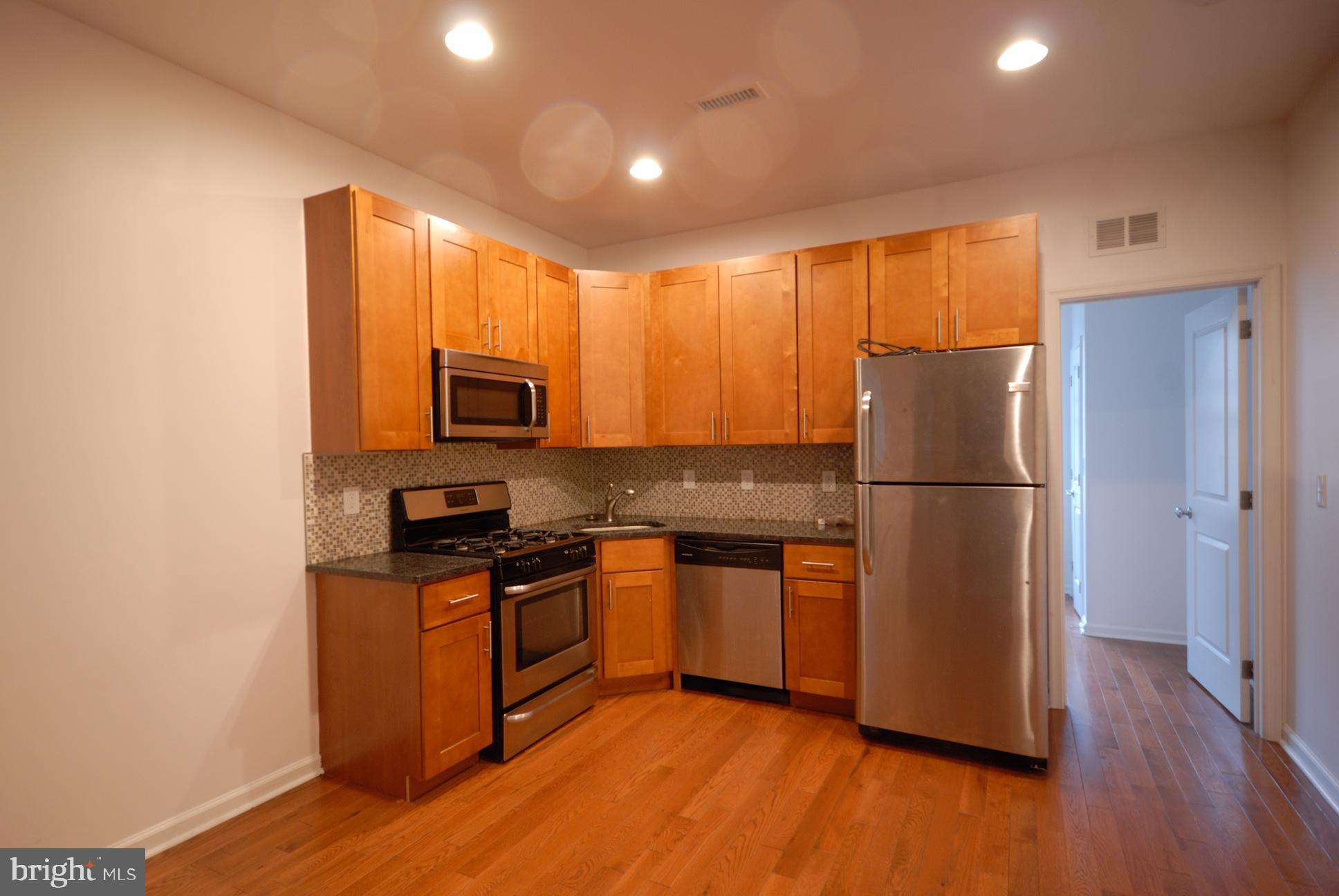 a kitchen with granite countertop wooden floors a stove and a refrigerator