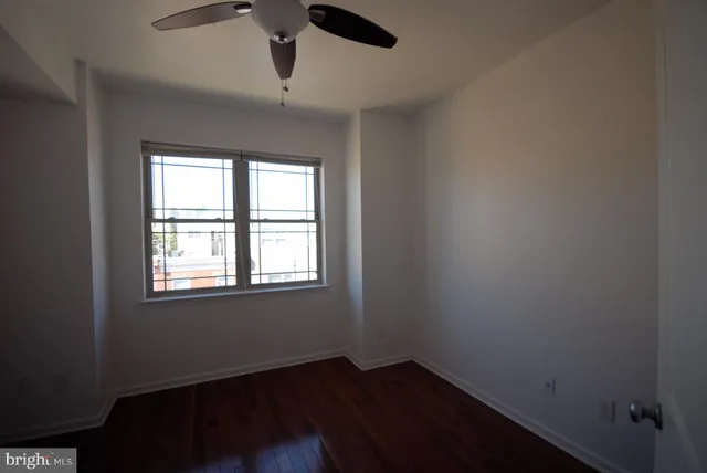 an empty room with wooden floor cabinet and windows