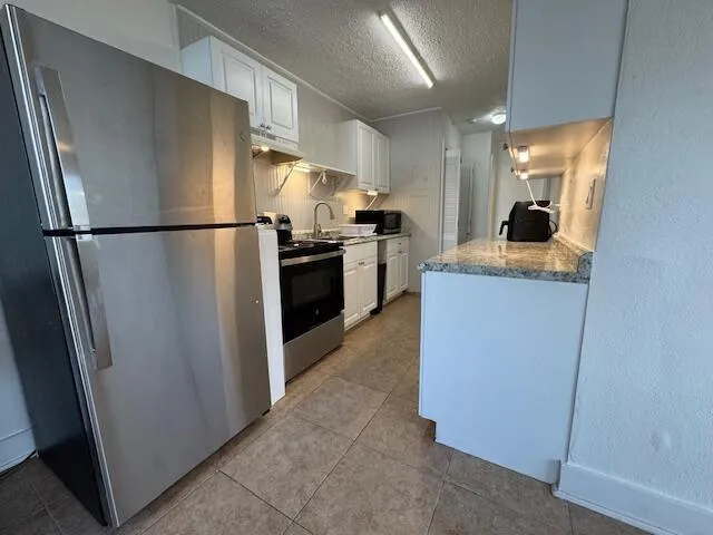 a kitchen with stainless steel appliances granite countertop a refrigerator and a stove top oven