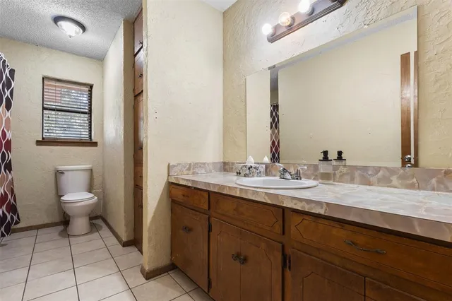 a bathroom with a granite countertop sink a toilet and a mirror