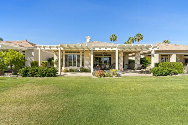 a view of a white house with a big yard and potted plants