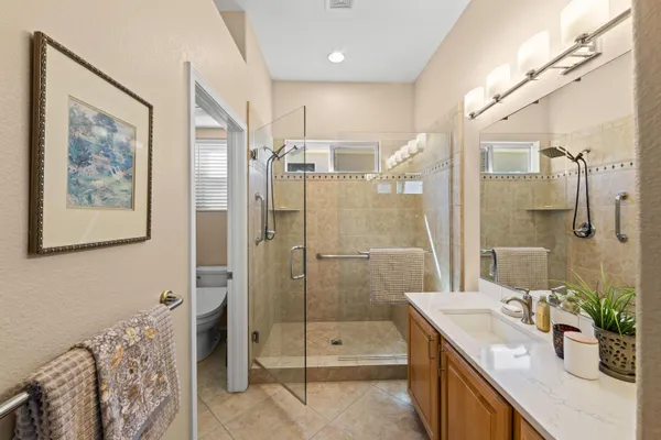 a bathroom with a granite countertop sink a mirror a glass door and shower