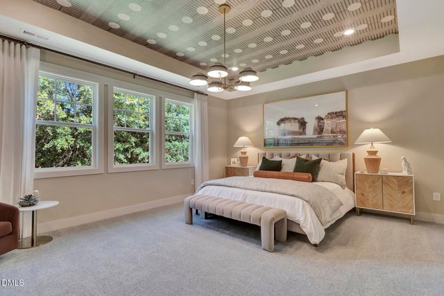a spacious bedroom with a bed chandelier and a large window