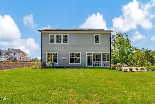 a front view of a house with a garden and trees