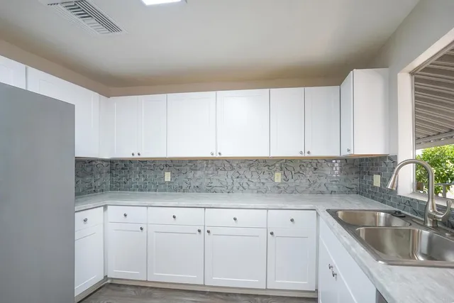a kitchen with granite countertop white cabinets and sink