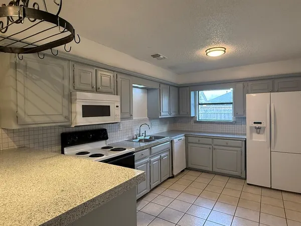 a kitchen with stainless steel appliances granite countertop a sink a stove a refrigerator a microwave and cabinets