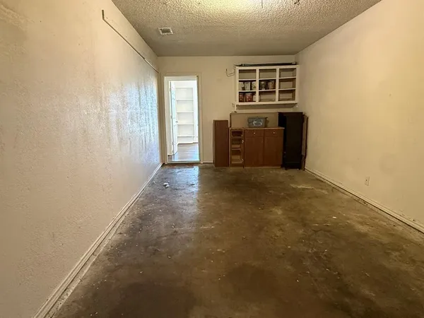 an empty room with windows and kitchen view