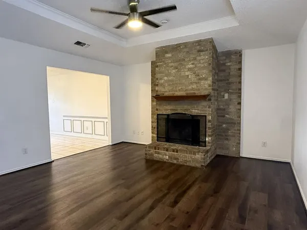 an empty room with wooden floor a fireplace and windows