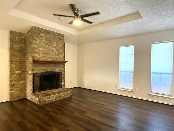 an empty room with wooden floor fireplace and windows