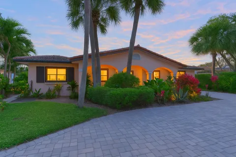 a front view of house with small garden and palm trees