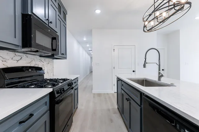 a kitchen with stainless steel appliances a sink dishwasher a stove and a microwave oven with wooden floor