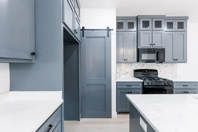 a kitchen with kitchen island granite countertop a stove top oven a sink and dishwasher
