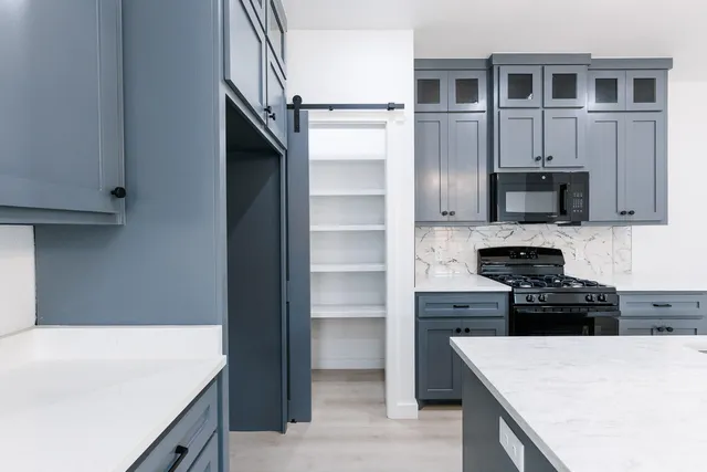 a kitchen with kitchen island granite countertop a stove top oven a sink and dishwasher