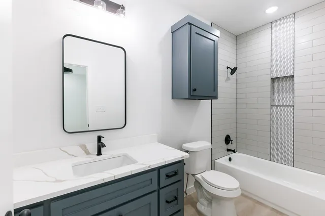 a bathroom with a granite countertop sink toilet and shower