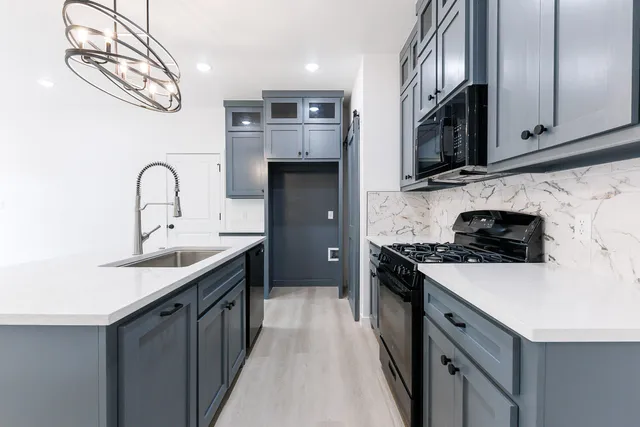 a kitchen with a sink and a stove top oven with wooden floor