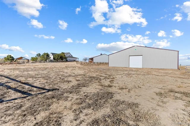 a view of a dry yard with trees in the background